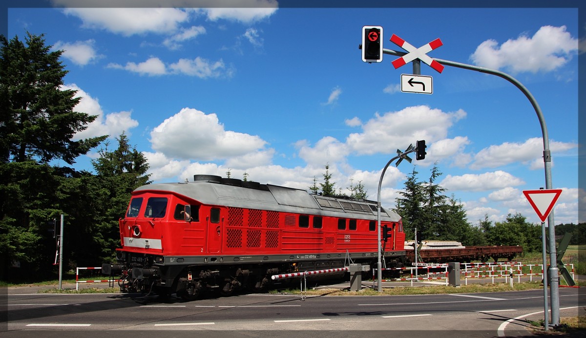232 469 mit ihrem grenzlastigen Zug in Klein Plasten am Bahnübergang in Richtung Kargow (Meckl.) aus Möllenhagen kommend am 30.06.2015